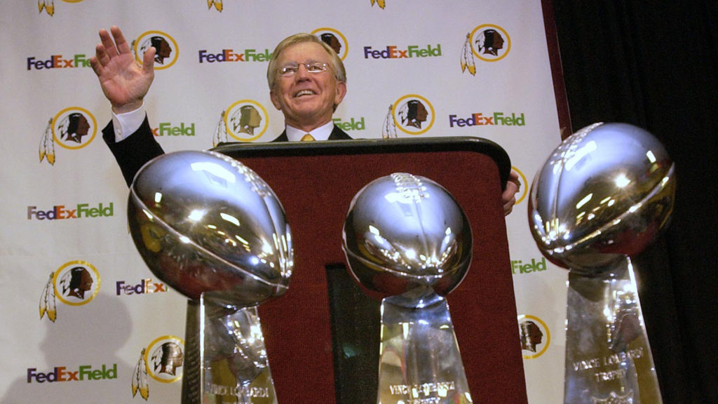 Joe Gibbs speaks with three Super Bowl trophies in foreground, after his return as the Washington Redskins head coach.